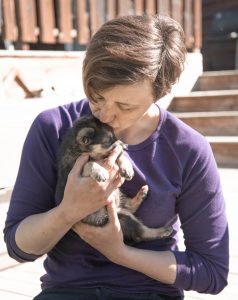 woman kissing small brown puppy
