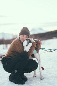woman cuddling husky in snow