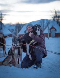 staff member cuddling two alaskan huskies before a dog sledding tour